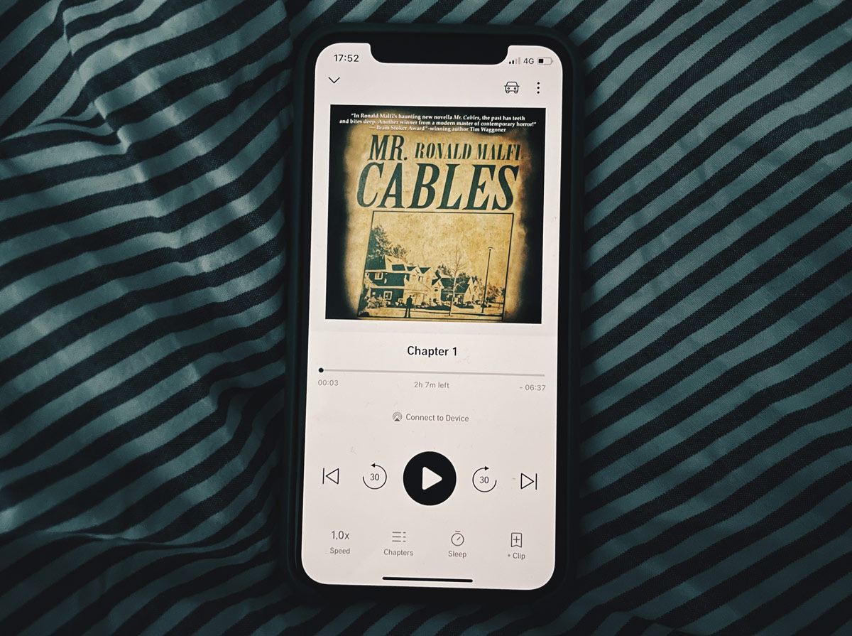 Boken Mr Cables i Audible på iPhone på ett täcke.